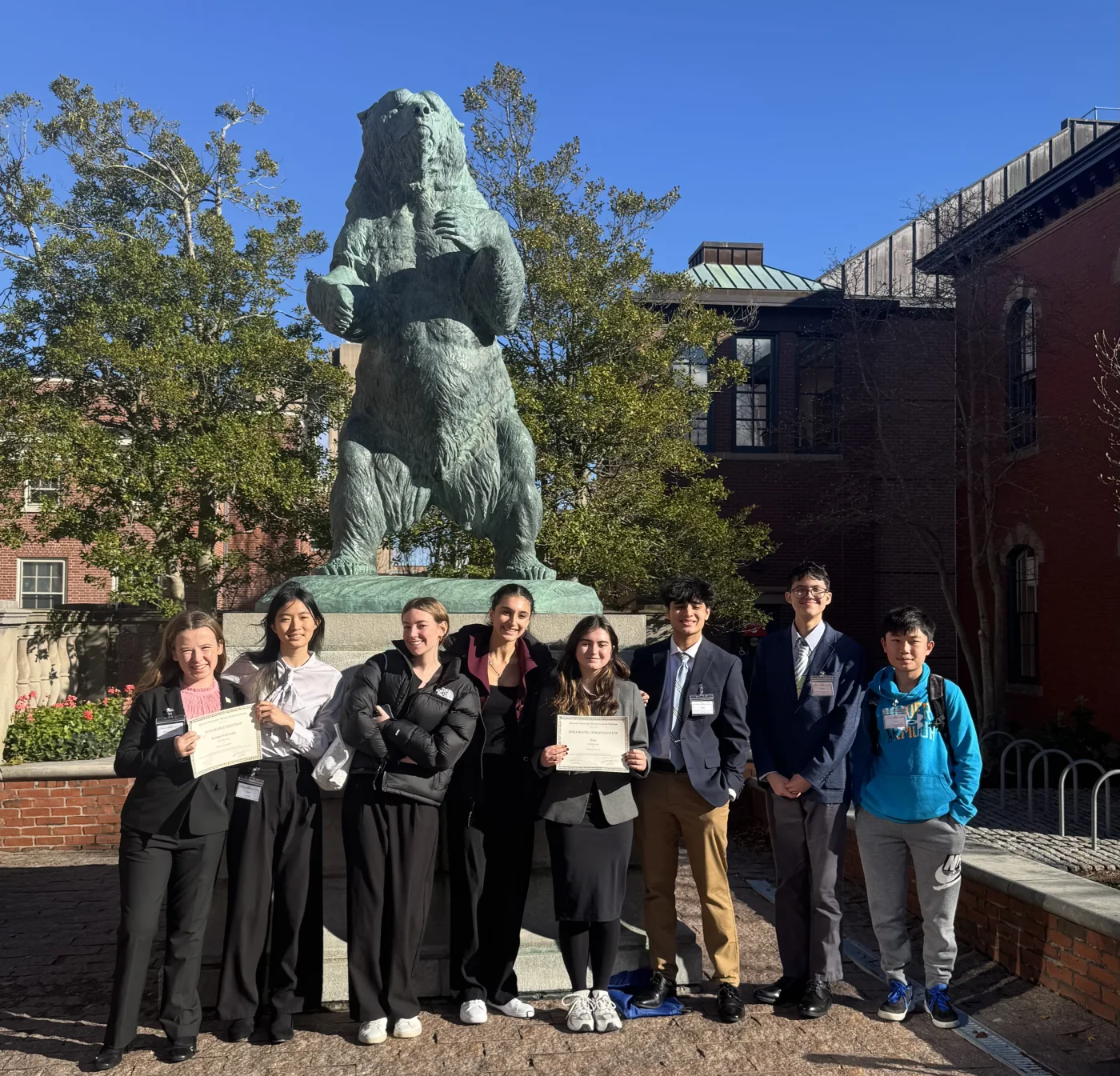A complete MUNSDG delegation smiling together beneath Brown University’s bear statue