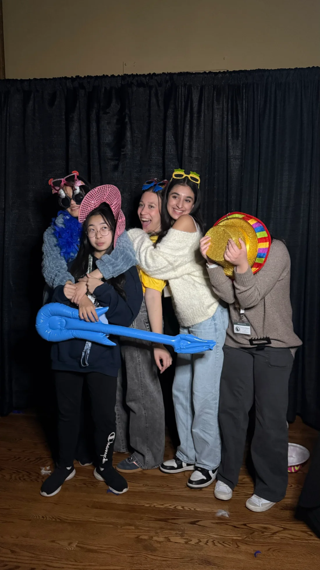 MUNSDG delegates smiling and hugging in party hats at a conference photo booth